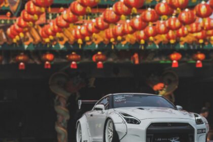 White sports car parked under festive lanterns White sports car parked under festive lanterns