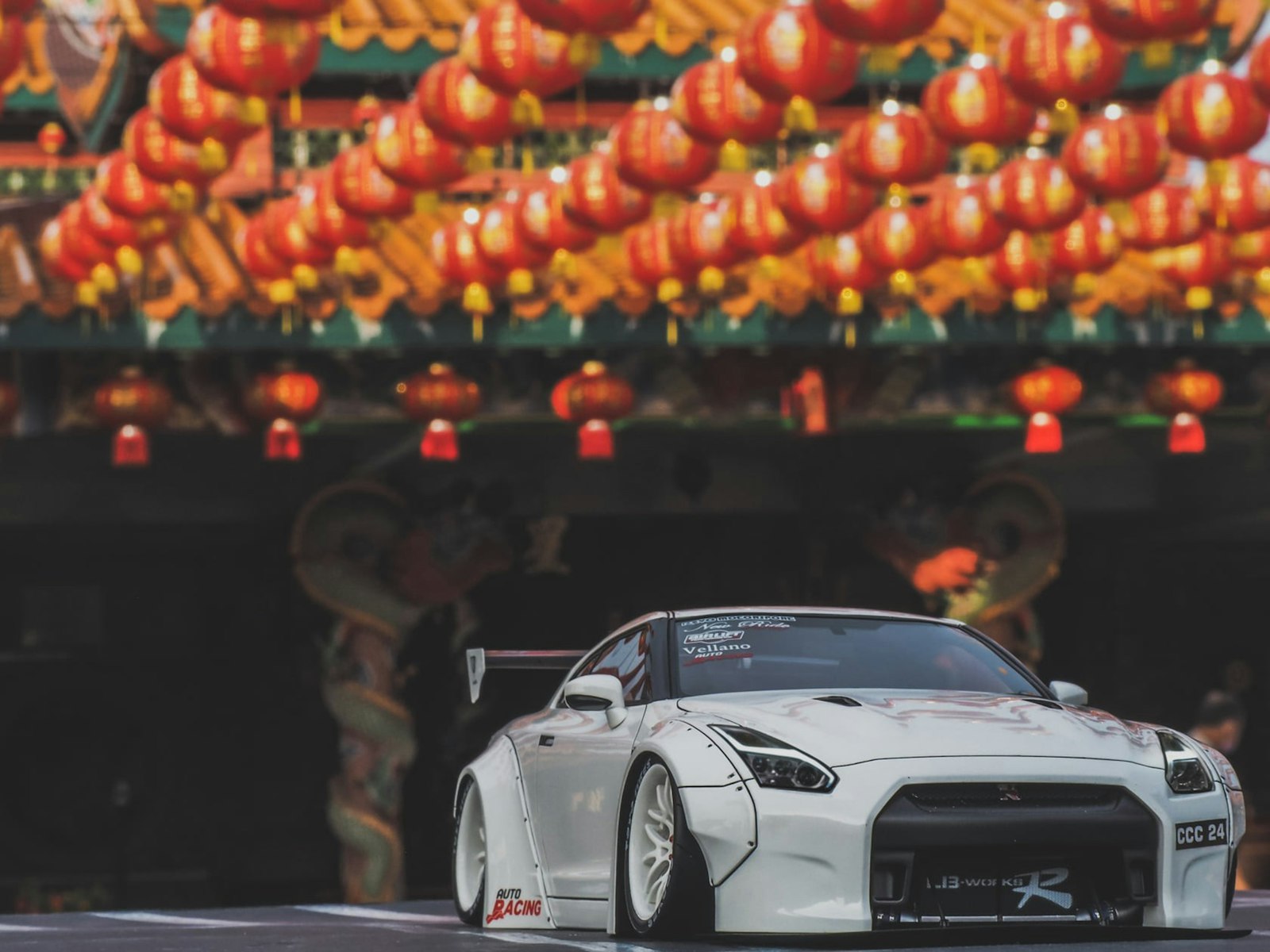 White sports car parked under festive lanterns