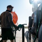 Man fueling a large truck at a gas station with a Texas sticker