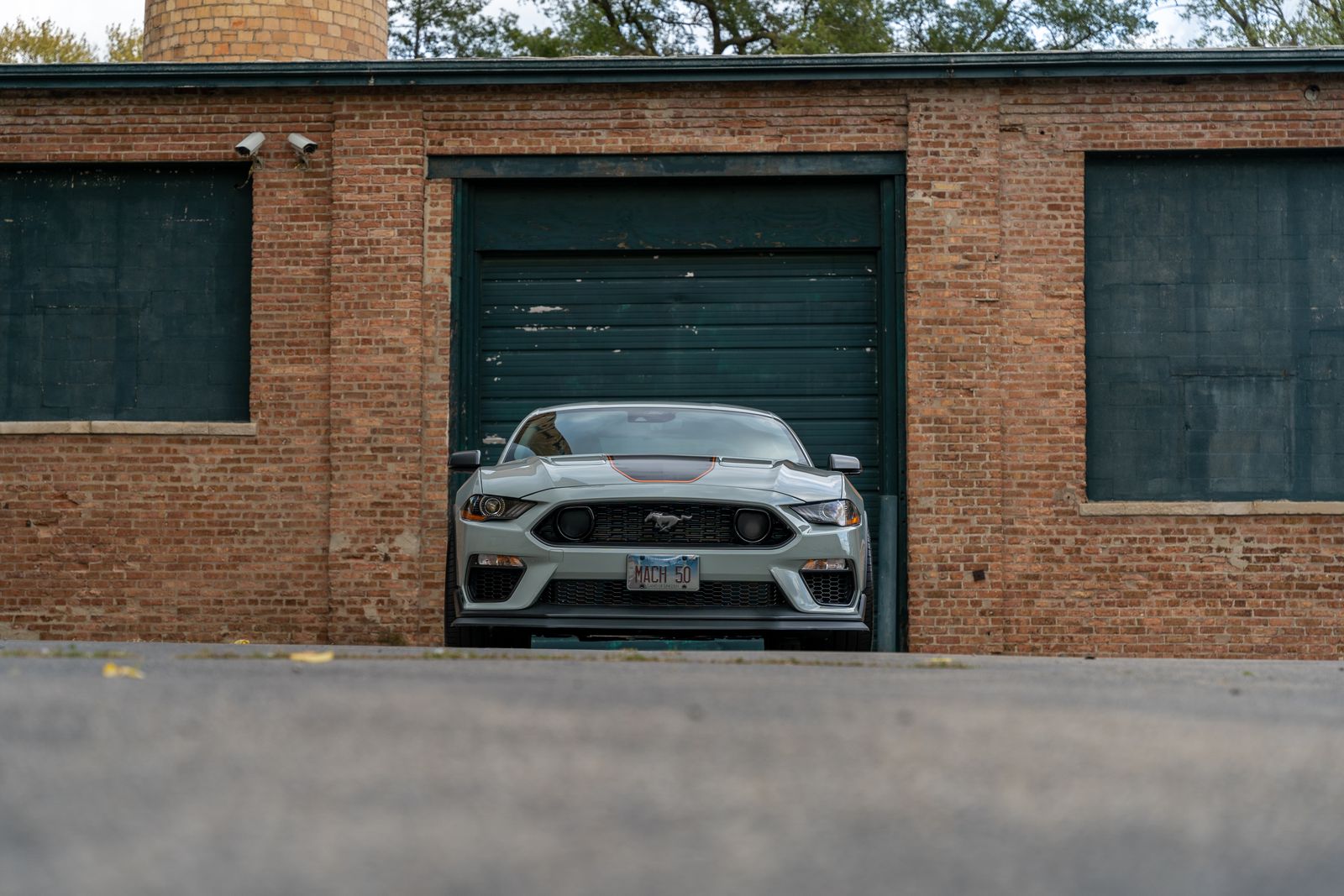 Silver Ford Mustang Mach 1 parked in front of brick garage