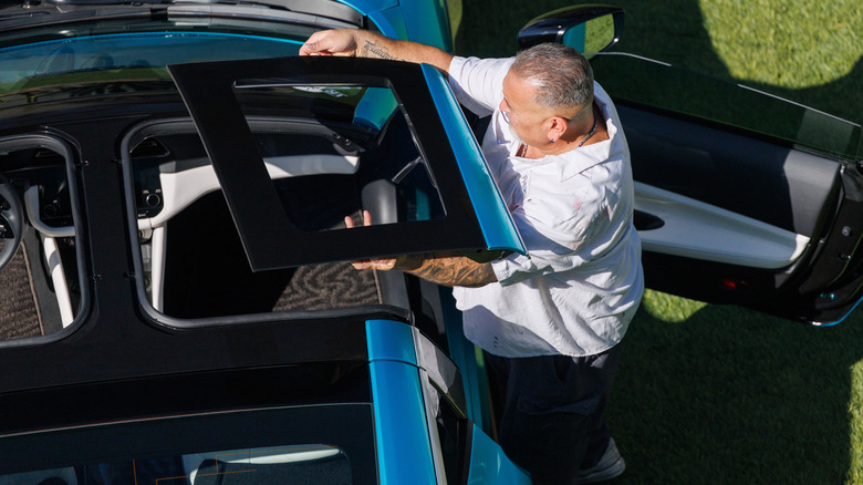 Man removing black T-top roof panel from blue Nissan Z sports car