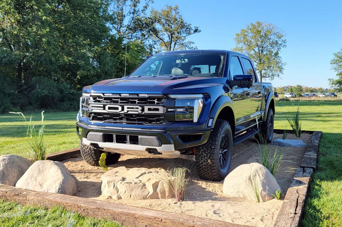 Blue Ford F-150 Raptor pickup parked on a rock and sand display