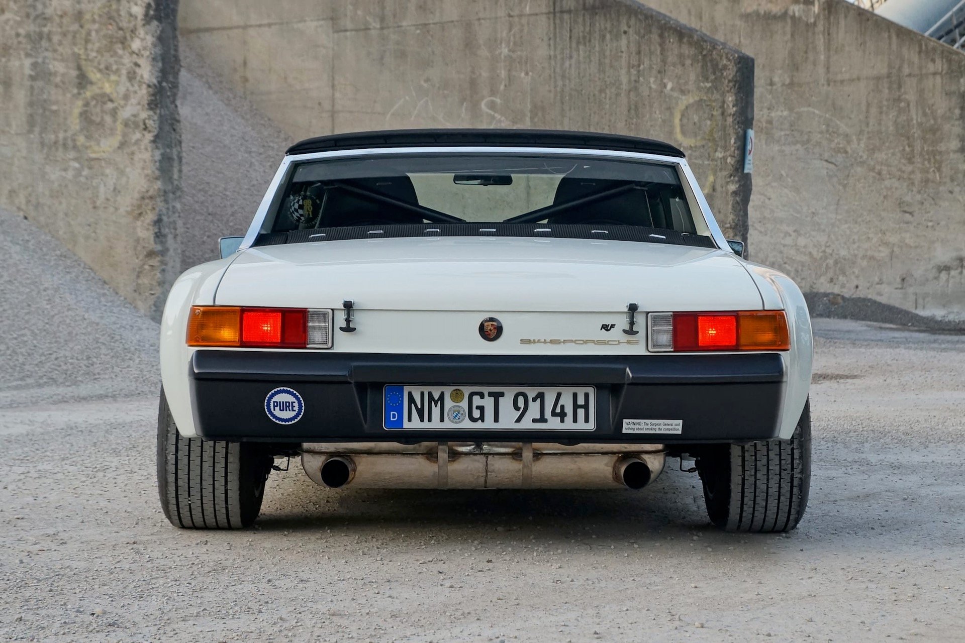 Rear view of a white Porsche 914 parked on gravel