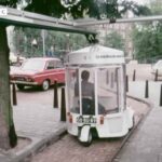 White Witkar electric car parked at a station on an Amsterdam street