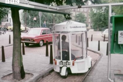 White Witkar electric car parked at a station on an Amsterdam street