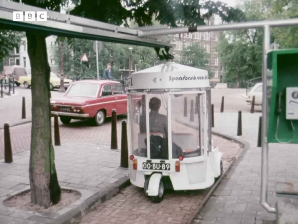 White Witkar electric car parked at a station on an Amsterdam street