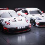 Two Manthey-liveried Porsche race cars on dark studio floor