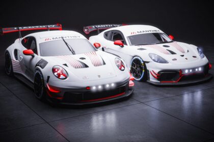 Two Manthey-liveried Porsche race cars on dark studio floor