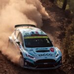 Ford rally car powers through dusty gravel corner