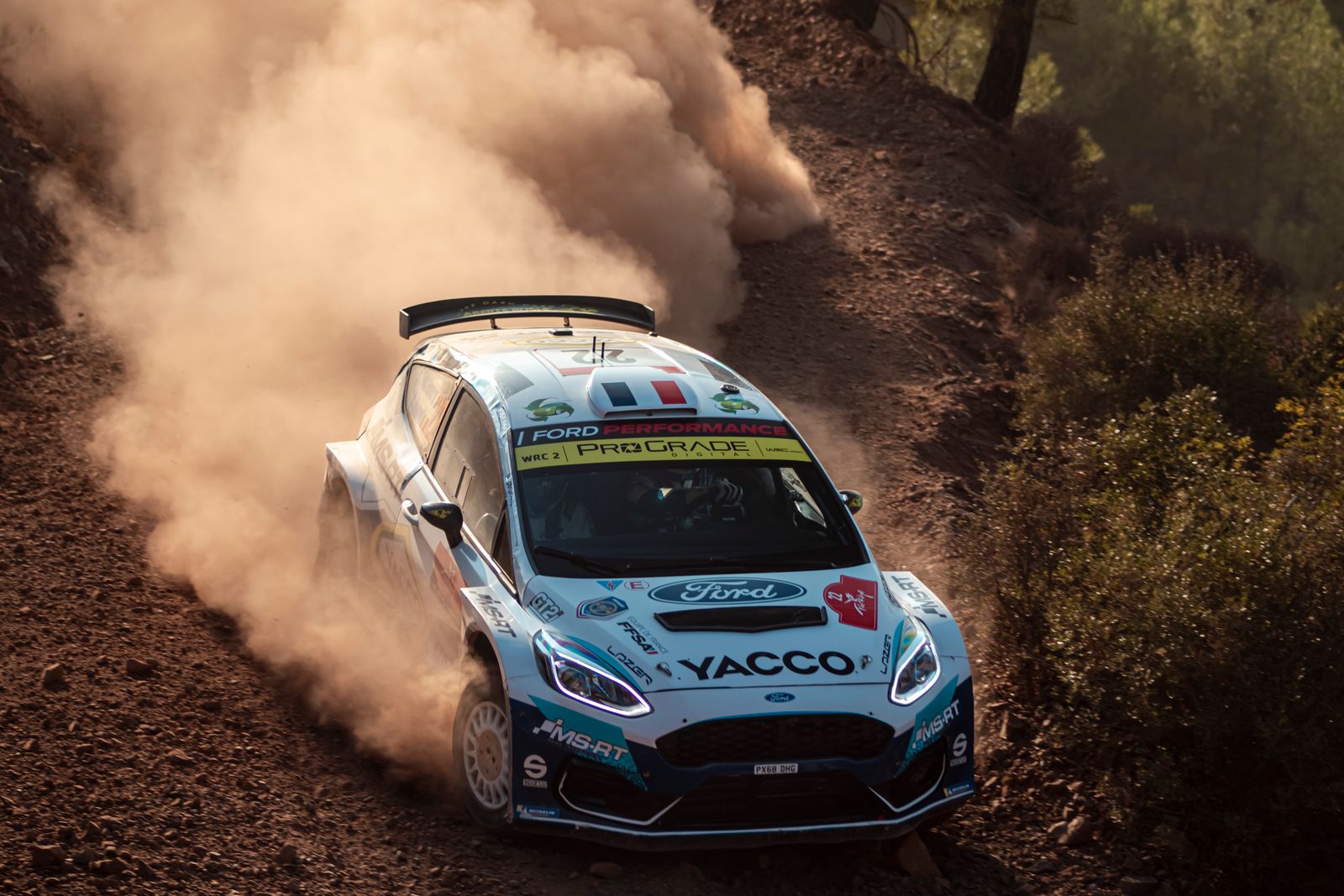 Ford rally car powers through dusty gravel corner