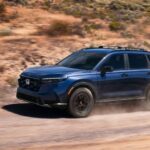 Blue Honda CR-V driving on a dusty dirt road