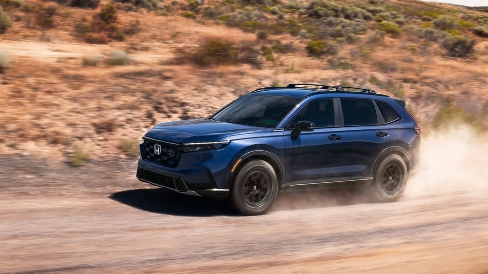 Blue Honda CR-V driving on a dusty dirt road