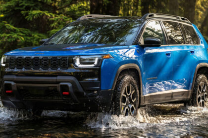 Blue Jeep Cherokee Trailhawk splashing through water on off-road trail