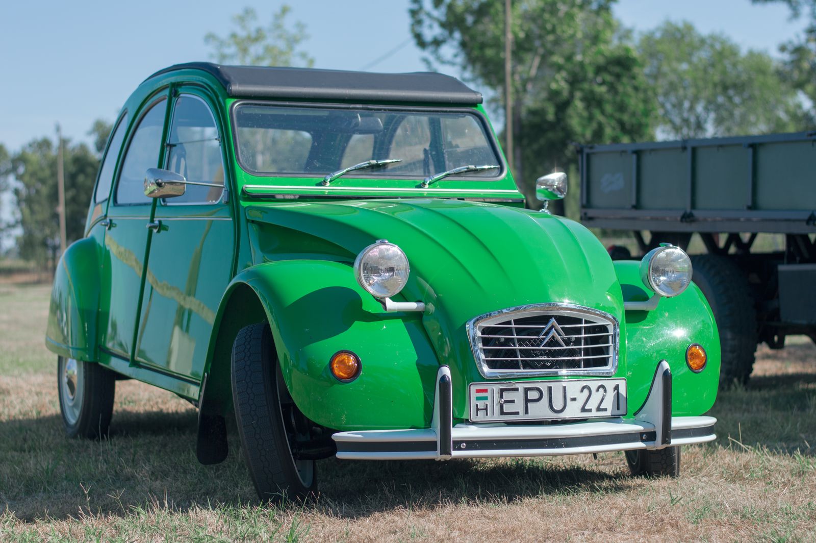 Green classic Citroen 2CV parked on dry grass