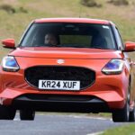 Orange Suzuki Swift hatchback driving on a UK road
