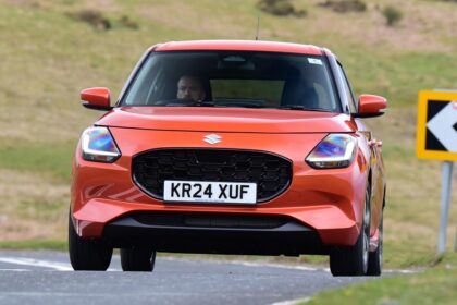 Orange Suzuki Swift hatchback driving on a UK road