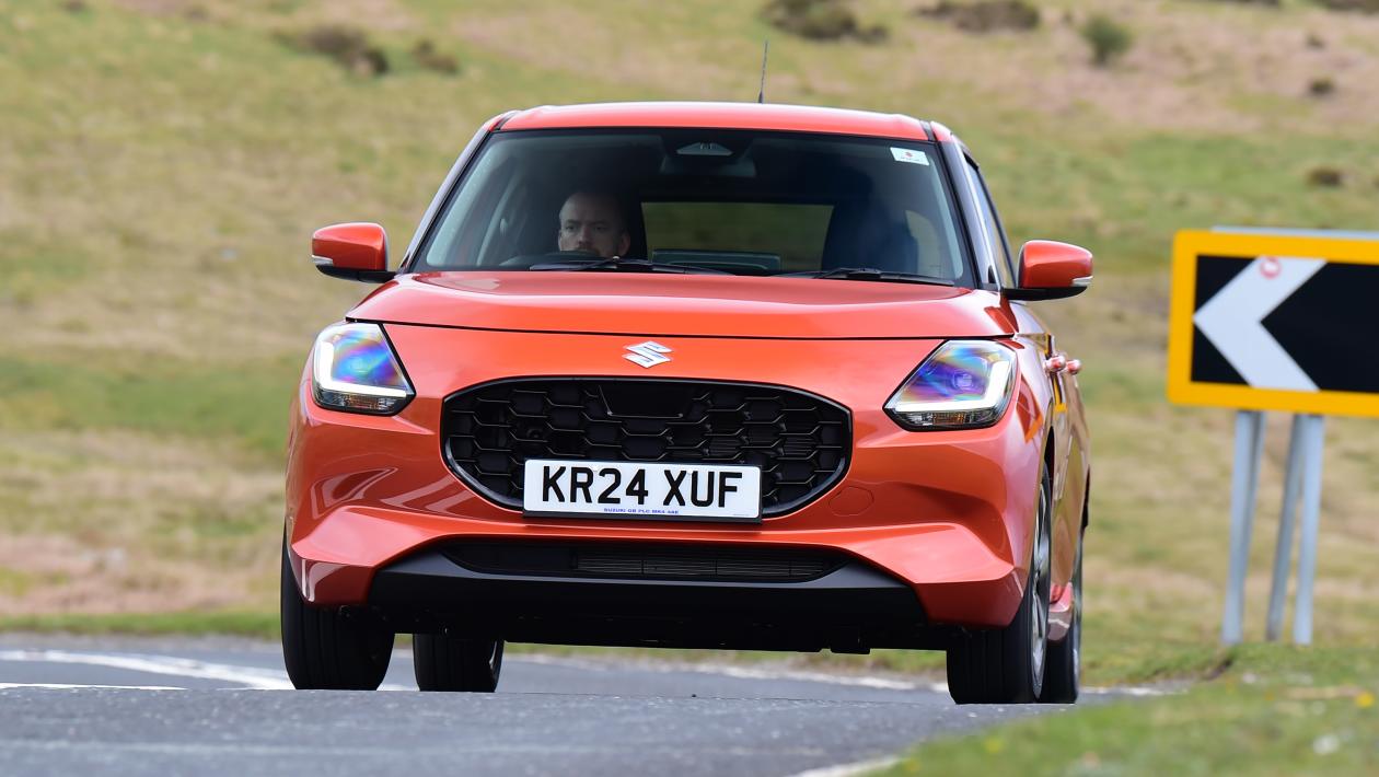 Orange Suzuki Swift hatchback driving on a UK road