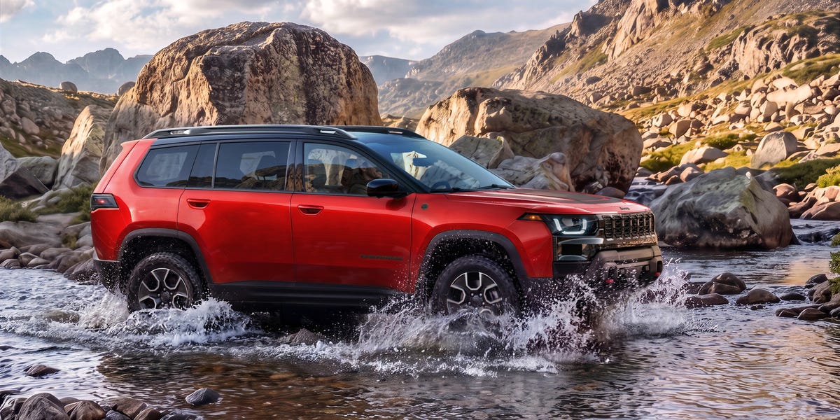 Red Jeep Cherokee Trailhawk driving through a rocky stream