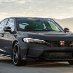 Dark gray Honda Civic Type R driving on a road at sunset