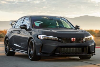 Dark gray Honda Civic Type R driving on a road at sunset