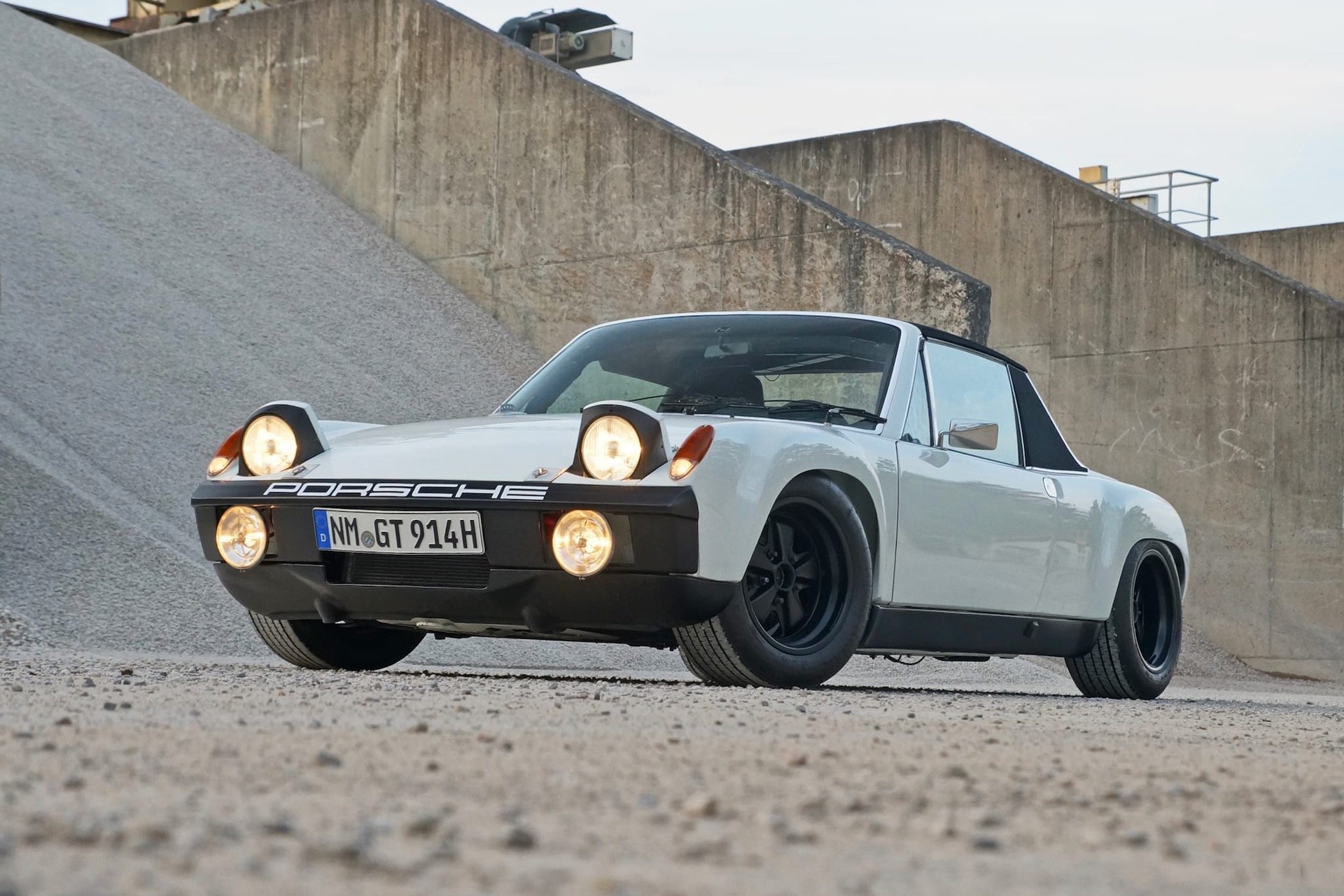 White Porsche 914 with pop-up headlights parked on gravel