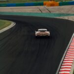 Aston Martin Racing car with colorful camo livery cornering on a racetrack
