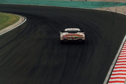 Aston Martin Racing car with colorful camo livery cornering on a racetrack