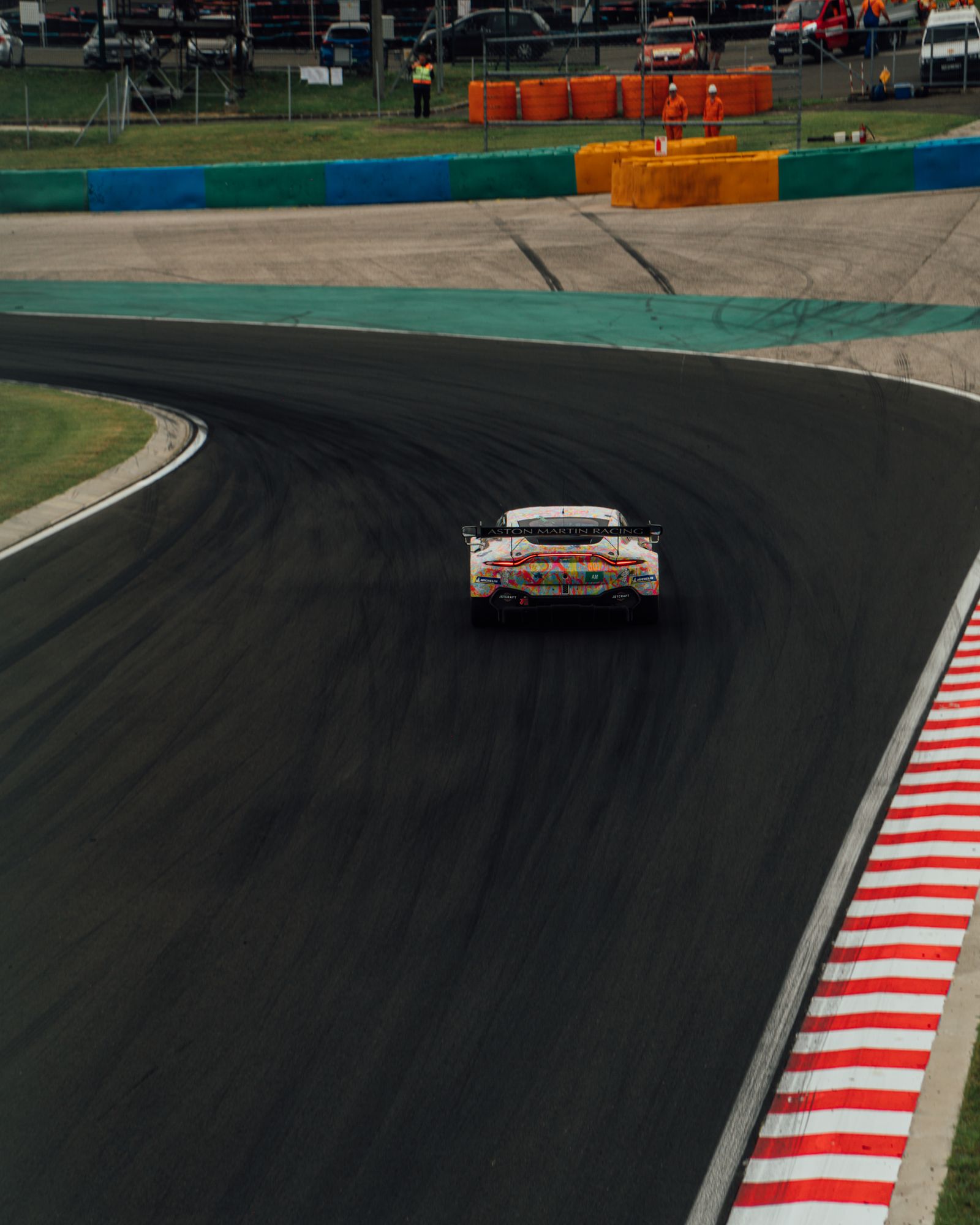 Aston Martin Racing car with colorful camo livery cornering on a racetrack